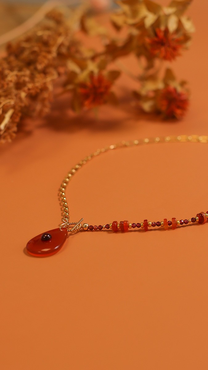Collana asimmetrica con catena in oro e pietre naturali di granato e corniola