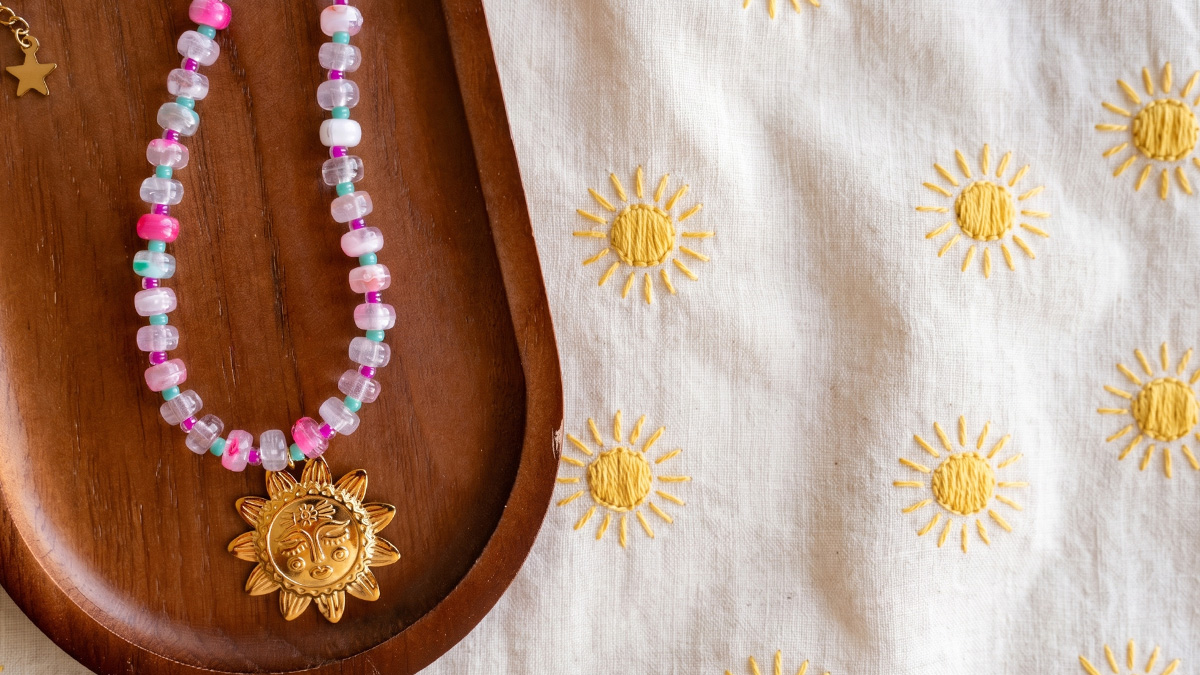 Collana con perline a disco in resina e pendente a forma di sole