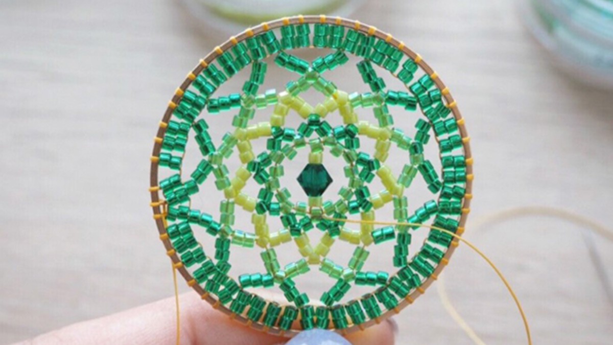 Pendente a forma di mandala con perline Miyuki di Petit bout de chou, a punto mattone. Pendente a forma di mandala con perline Miyuki di Petit bout de chou, a punto mattone.